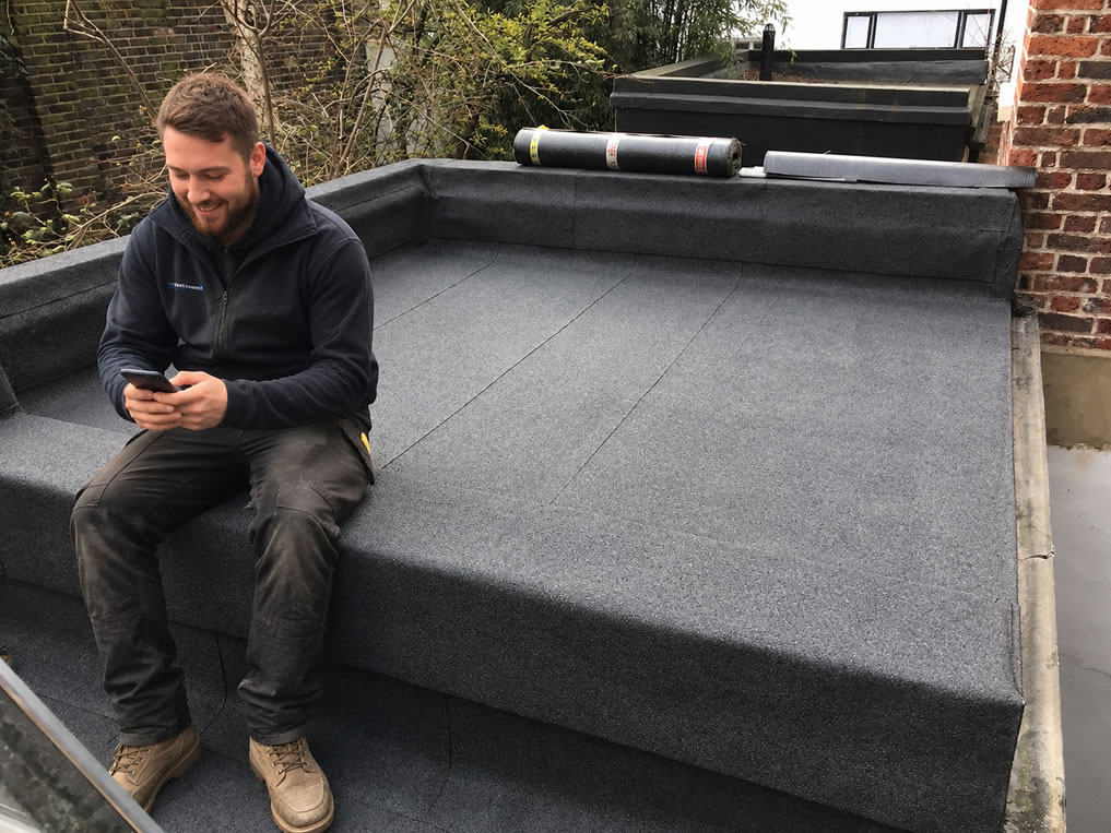 Felt roofing leads - roofer sitting and looking at leads on mobile phone